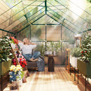 Woman sitting in a 12 x 8 greenhouse with plants and flowers around