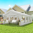 White 13 x 26 outdoor canopy tent set up on a grassy area in front of a house with tables and chairs underneath.