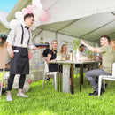 People enjoying a meal outdoors under a tent with balloons and greenery.
