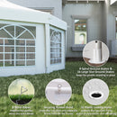 White gazebo tent with spiral ground stakes, wind ropes, and securing rubber band on grass in front of a house.