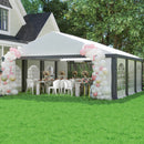 Outdoor 20 x20 event tent setup with a canopy tent, tables, chairs, and balloon arches in a garden.