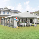 Outdoor party setup with a large white canopy tent on a grassy lawn, featuring tables, chairs, and balloons.