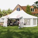 White decagonal party tent with decorative arches and balloons in a garden setting.