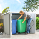 Man placing a green trash and recycling  bin into a 5x3 storage shed with a blue bin inside.
