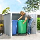 Man placing a green trash bin into a 5x3ft metal storage shed with a blue bin inside.