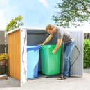 Man placing a green trash and blue recycling bins into a 5x3 storage shed with double swing doors.