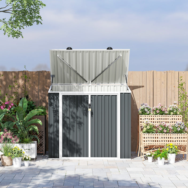 Gray metal storage shed for garbage and recycling with a lifted roof lid in a garden setting with a lock on it. 