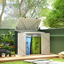 Outdoor storage shed with open lid containing blue and green trash and recycling bins, surrounded by plants and trees.
