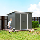 Child playing with a soccer ball in front of a metal garden storage shed in a grassy area.