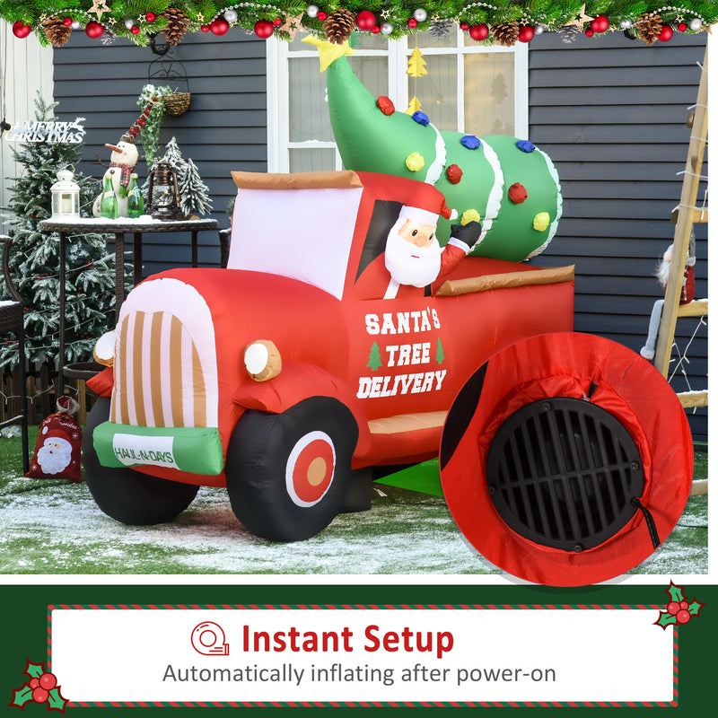 Large Christmas inflatable display  scene with a red truck carrying a decorated tree, featuring Santa Claus, on a snowy outdoor setting.