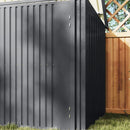 Grey metal storage shed with a wooden fence in the background