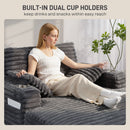 Woman sitting on a gray sofa with built-in cup holders, holding a glass.