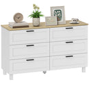 White dresser with wooden top, decorative items including a plant and picture frames.