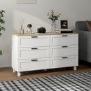 White dresser with wooden top in a room with a gray sofa and decorative items.
