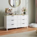 White dresser with decorative items in a room with a mirror and flowers.