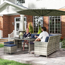 Two people sitting at a patio table with outdoor furniture in front of a house.