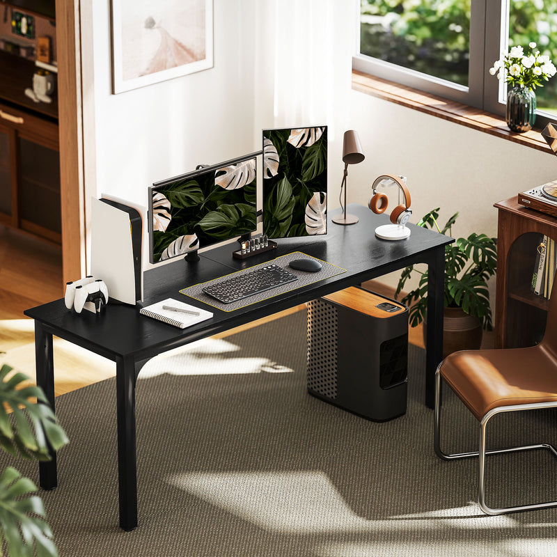 Modern home office setup with a black desk, computer setup, and decor.