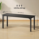 Black dining table with measurements and weight capacity on a wooden floor.