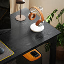 Orange and white headphones on a stand on a dark desk with a plant in the background