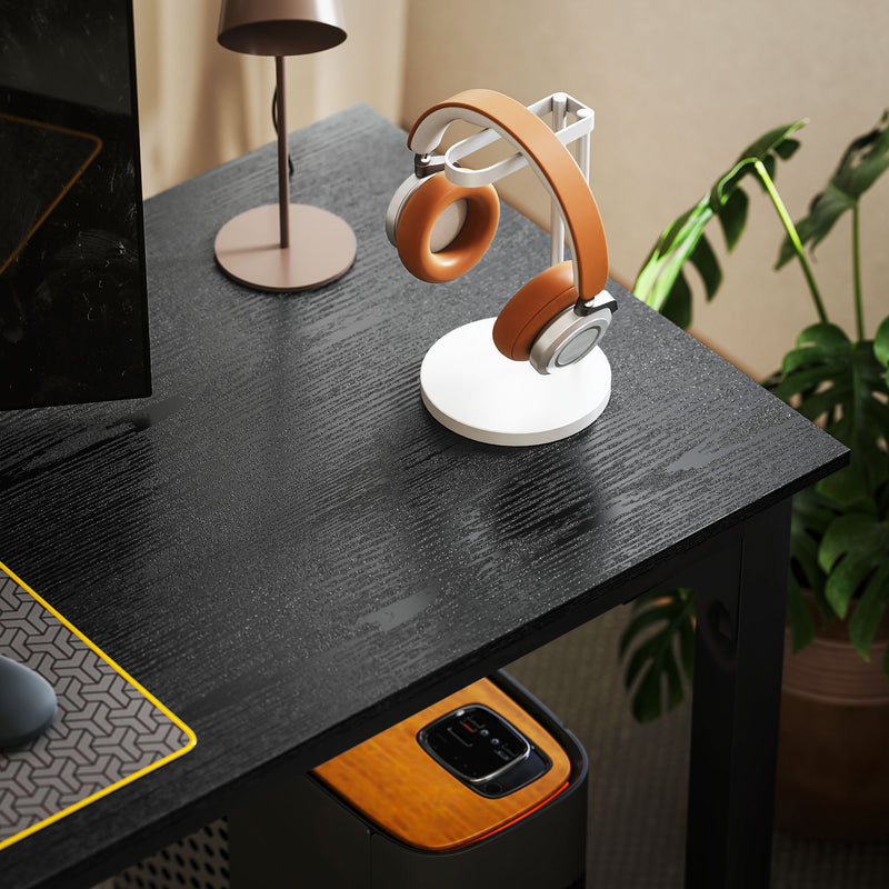 Orange and white headphones on a stand on a dark desk with a plant in the background