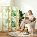 Woman reading a book in a cozy room with a decorative screen and cat.