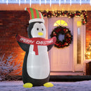 Giant Inflatable Christmas display penguin with a 'Merry Christmas' scarf in front of a decorated house.