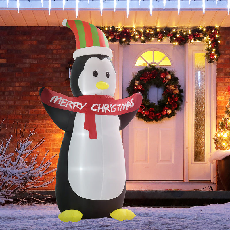 Giant Inflatable Christmas display penguin with a 'Merry Christmas' scarf in front of a decorated house.