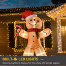 Inflatable gingerbread man decoration with LED lights in front of a house decorated with string lights.