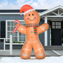 Inflatable gingerbread man decoration with a Santa hat and candy cane in front of a house.