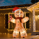 Inflatable gingerbread man decoration with a candy cane in front of a house with string lights.
