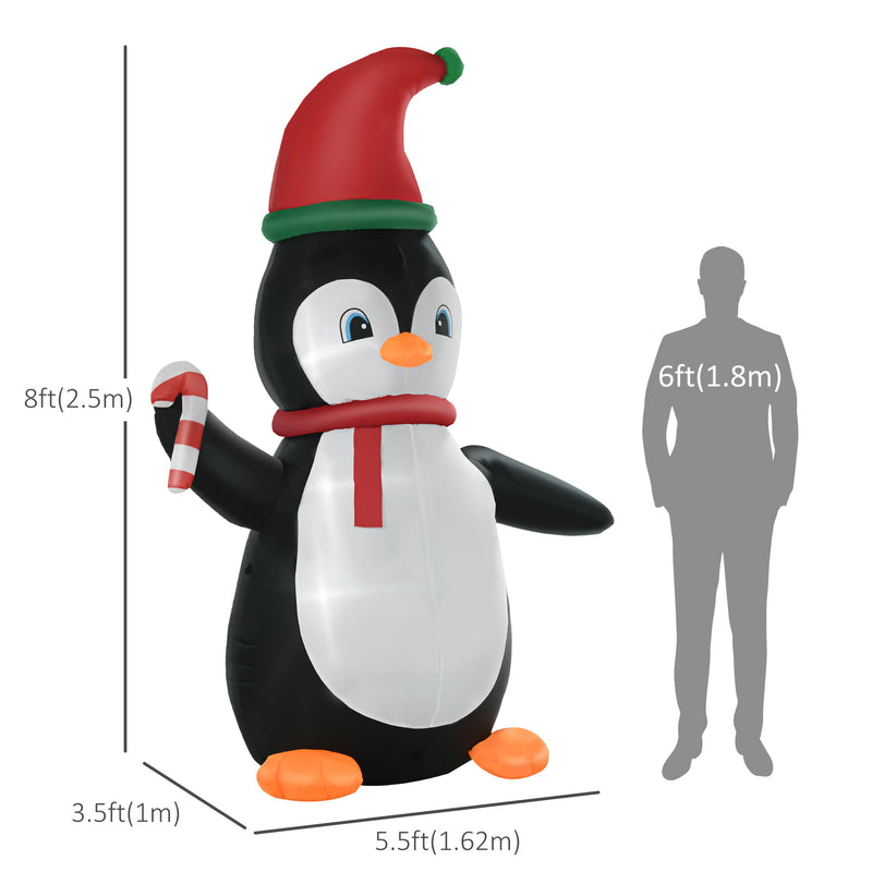 Inflatable penguin Christmas display with holiday hat and scarf, shown with a person for scale on a white background.