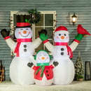 Inflatable snowman family with a smaller snowman and a bird in front of a house.