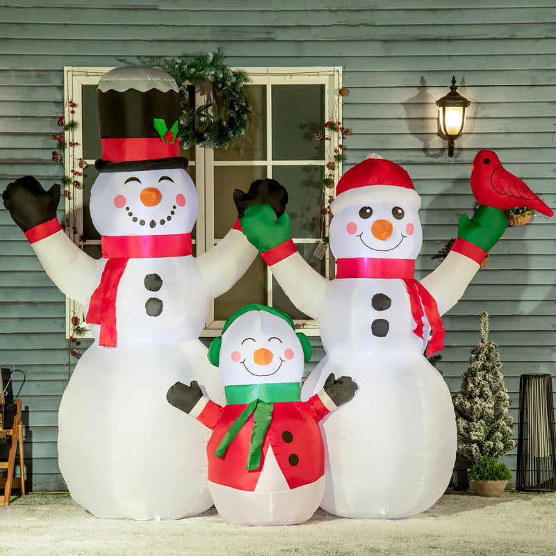 Inflatable snowman family with a smaller snowman and a bird in front of a house.