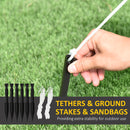 Hand holding a tent stake with tethers and sandbags on grass