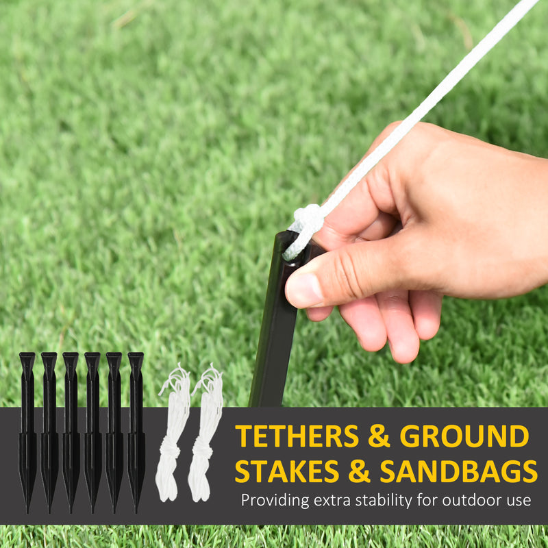 Hand holding a tent stake with tethers and sandbags on grass