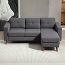 Gray sectional sofa with grey corduroy fabric in a room with a textured wall and rug.