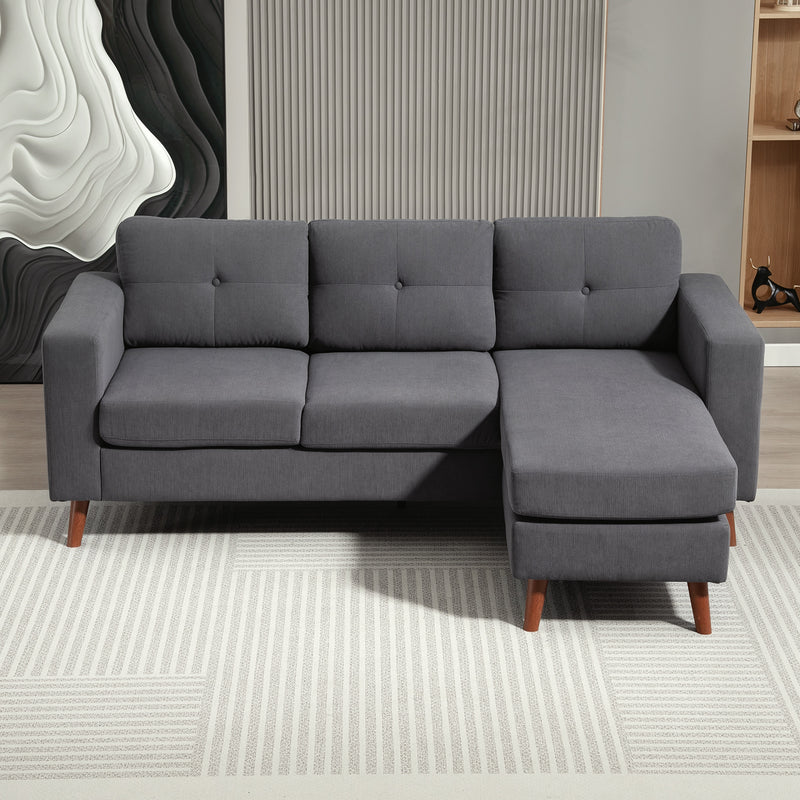 Gray sectional sofa with grey corduroy fabric in a room with a textured wall and rug.
