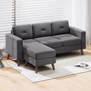 Gray sectional sofa L-Shaped with corduroy fabric material and wooden legs in a room with light wood flooring and white blinds.