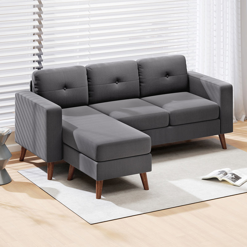 Gray sectional sofa L-Shaped with corduroy fabric material and wooden legs in a room with light wood flooring and white blinds.