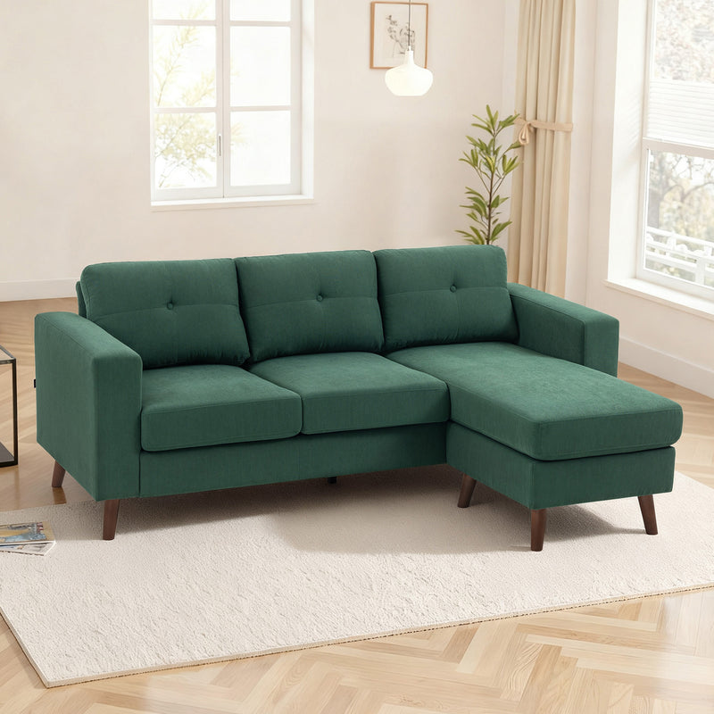 Green sectional sofa in a living room setting with decor elements.