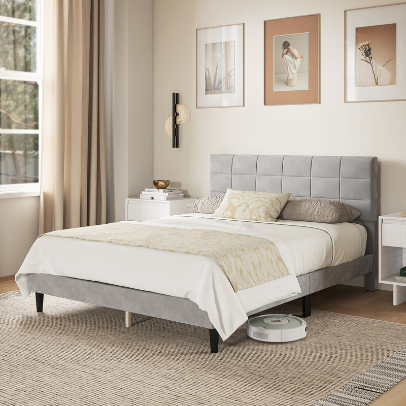 Modern bedroom with a gray upholstered bed, white bedding, and a robot vacuum cleaner.