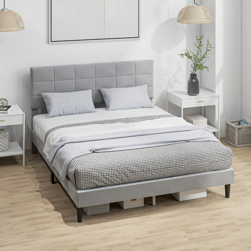 Gray upholstered bed with white bedding in a room with white walls and wooden flooring.