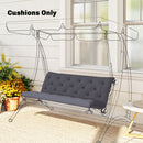 Gray swing with cushions on a patio with flowers and a table.