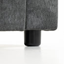 Close-up of a dark gray ribbed fabric upholstered furniture corner meeting a black cylindrical leg on a white studio background.