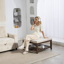 Woman sitting on an ottoman bench in a modern living room wearing headphones.