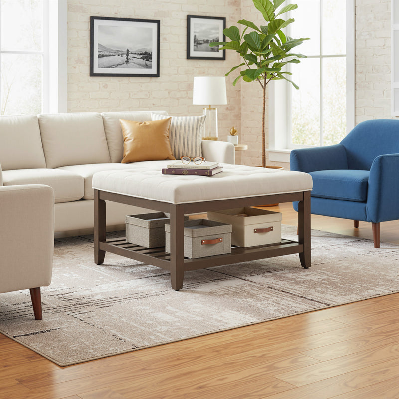 Living room with beige sectional sofa, blue armchair, and wooden coffee table with tufted upholstered top.