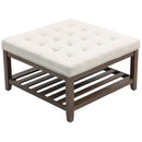 Square ottoman with tufted white cushion and wooden frame on a white background