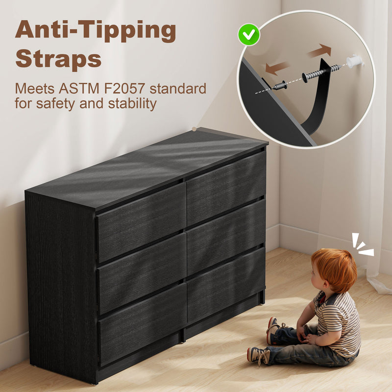 Black dresser with anti-tipping straps and a child sitting on the floor.