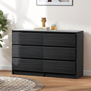 Black dresser with 6 drawers and decorative items on top in a room setting