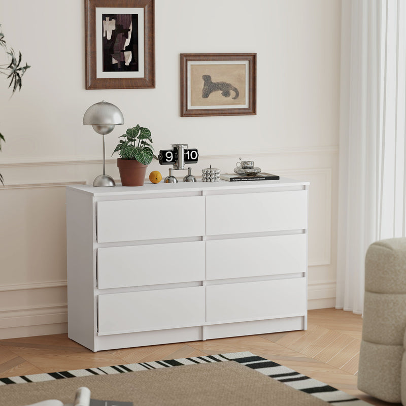 White 6-drawer dresser in a room with decor elements like a lamp, plant, and clock.